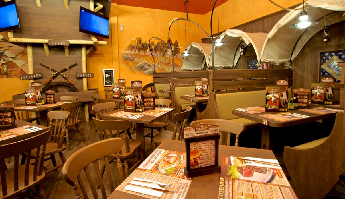 Old Wild West Custom-made furniture for a Western-style restaurant, including wooden tables and chairs, metal fences and bars.