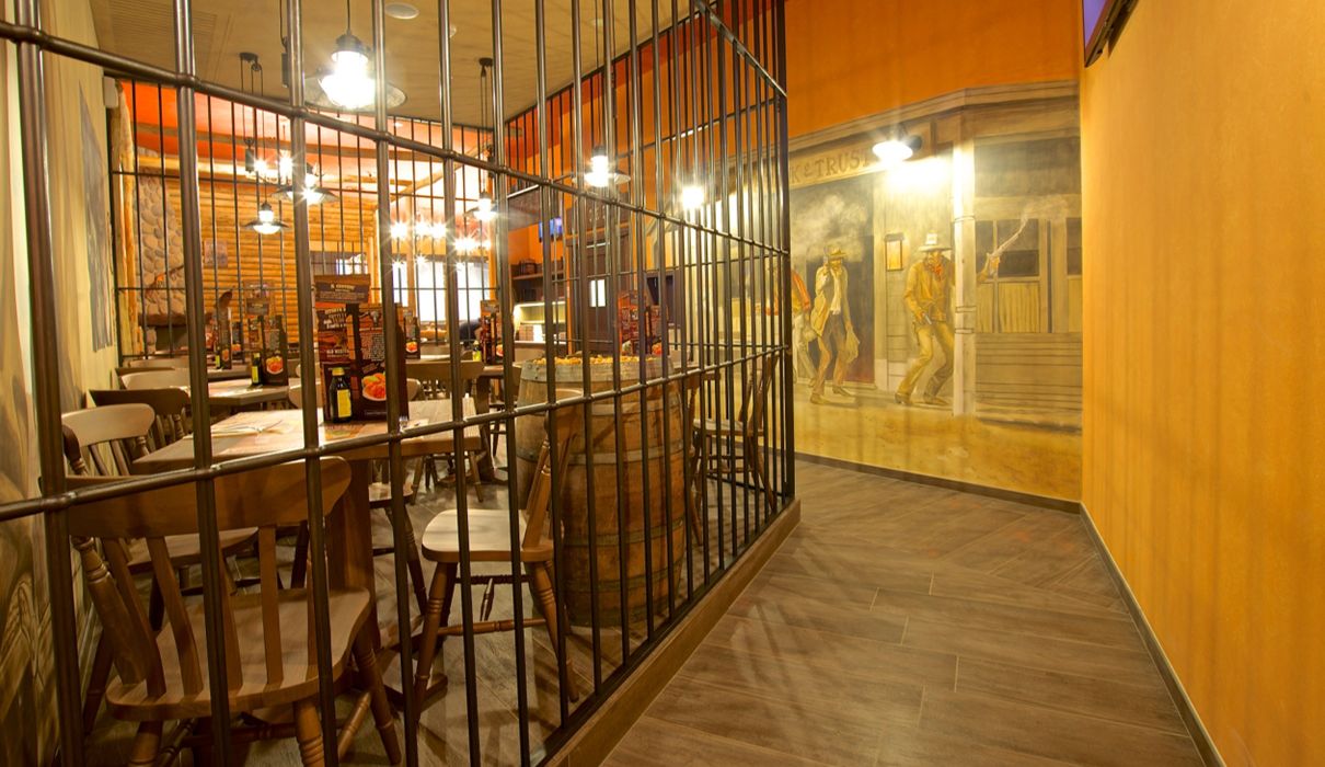Old Wild West Custom-made furniture for a Western-style restaurant, including wooden tables and chairs, metal fences and bars.
