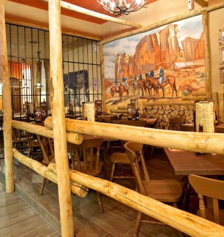 Custom-made furniture for a Western-style restaurant, including wooden tables and chairs, metal fences and bars.