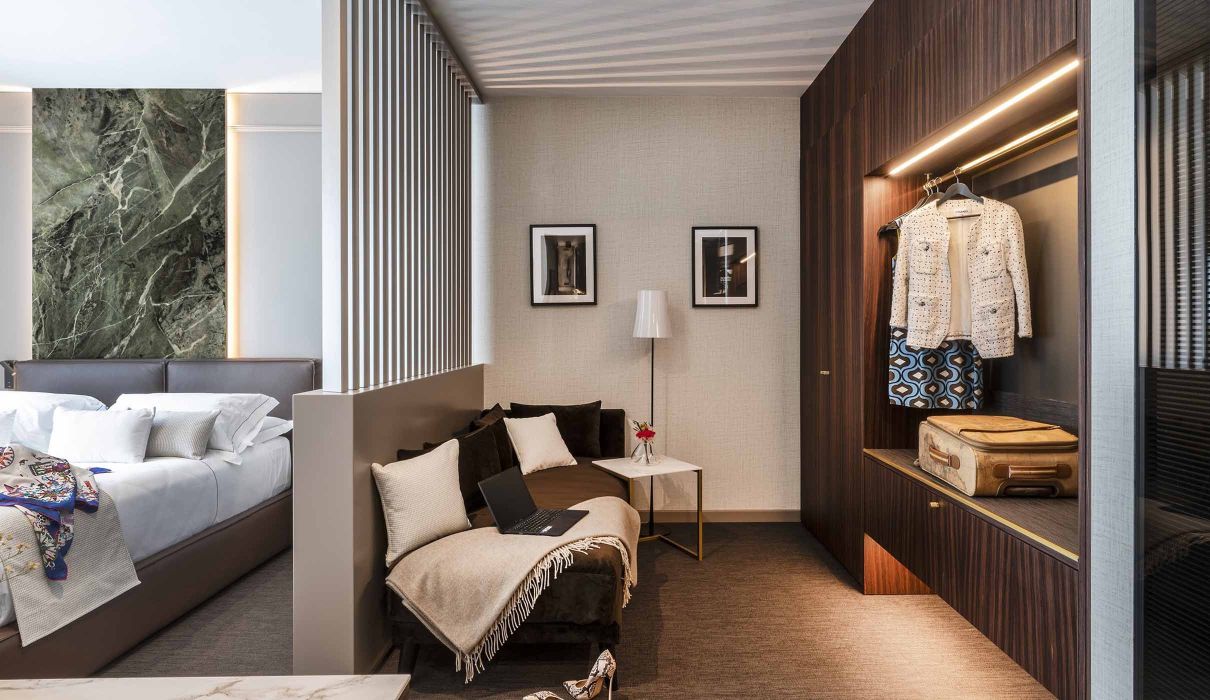 Custom-made hotel furnishings: wardrobe area with open wardrobe and sofa